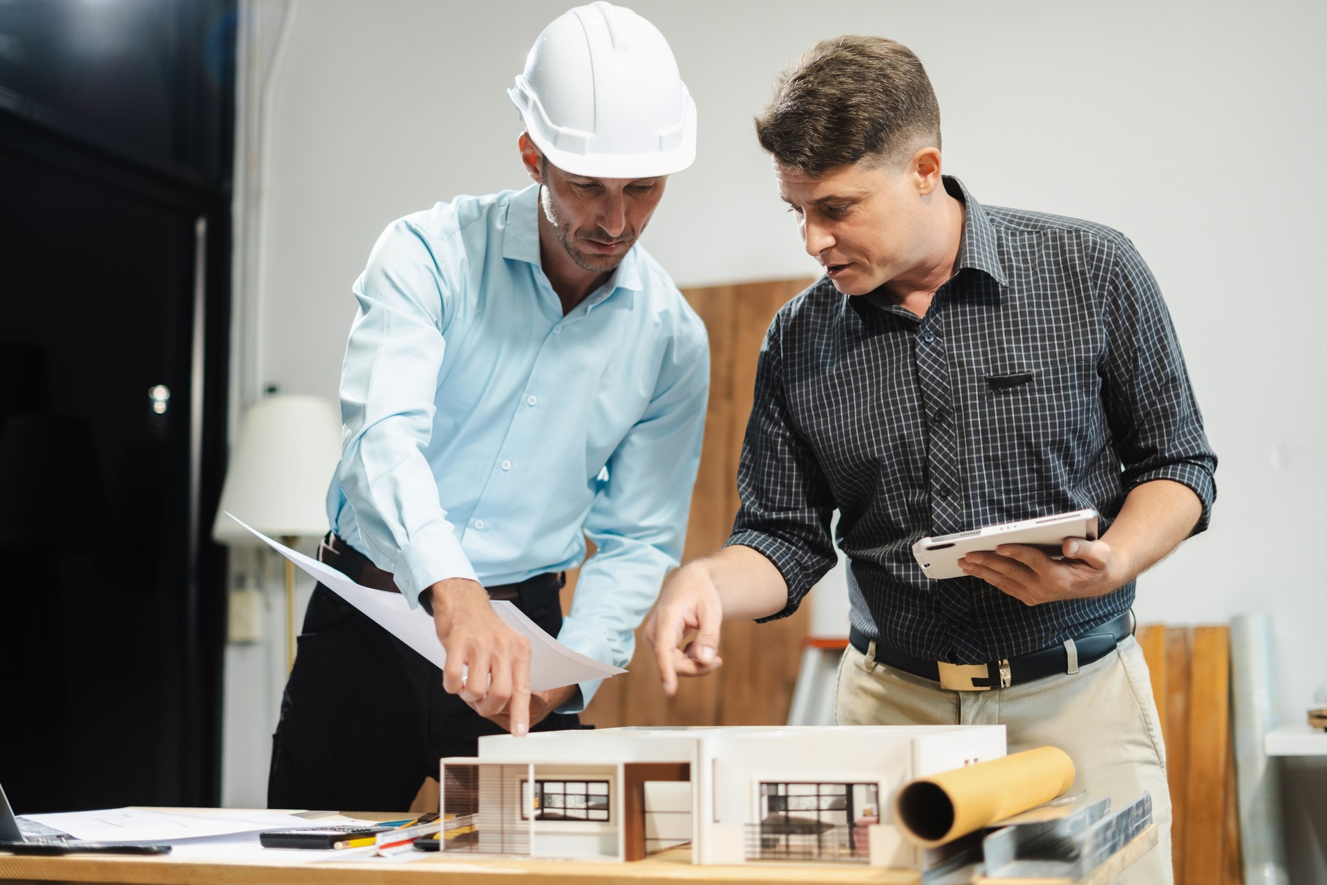 Architect caucasian man working, blueprint meeting for project working with partner on model building at company office.